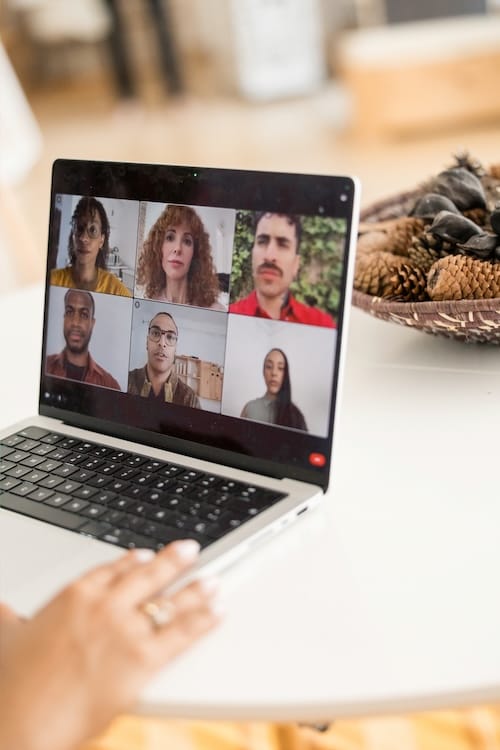 A laptop on a table showing a six-person video call